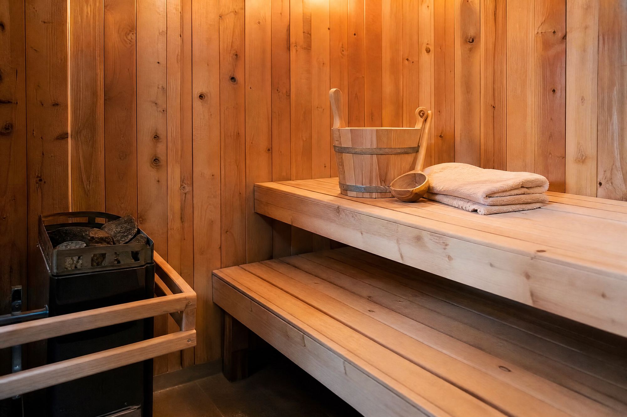 Intérieur de sauna en bois avec banquettes, poêle et seau traditionnel